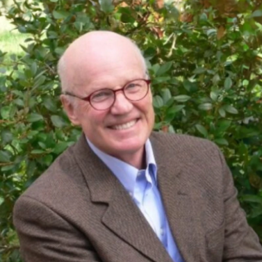 Portrait of Robert Paarlberg, headshot of a bold man wearing red glasses and smiling at the camera.